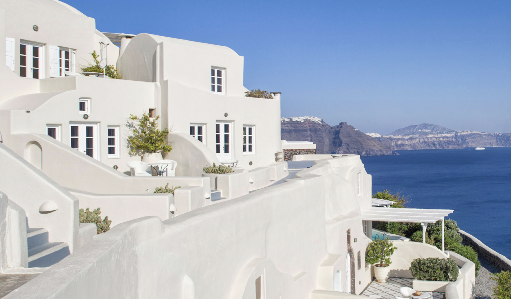 White hotel on cliff overlooking blue water